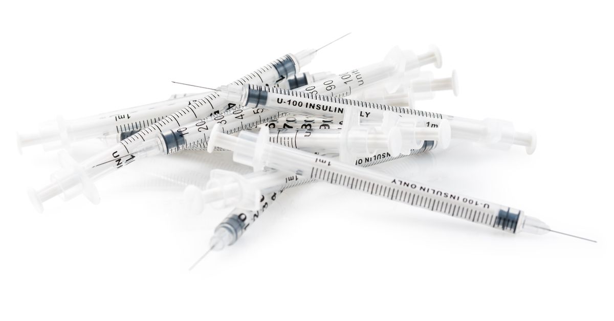 A pile of empty insulin syringes is shown against a white background.