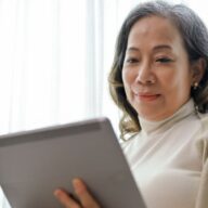 A 65 year old Asian woman looks at medicare deductible FAQs on her tablet.