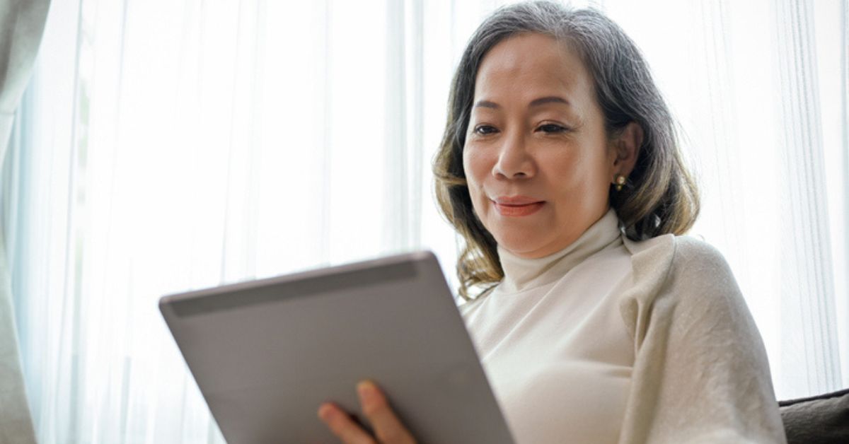 A 65 year old Asian woman looks at medicare deductible FAQs on her tablet.